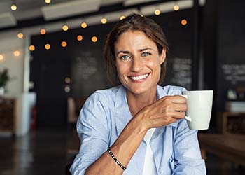 smiling woman holding a white coffee mug