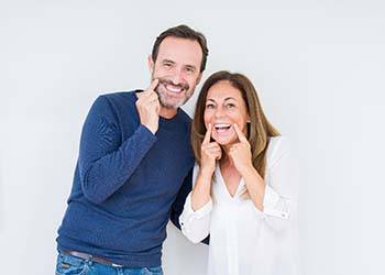 man and woman pointing to their smiles