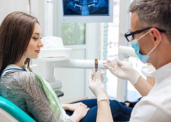 implant dentist in Medford showing a dental implant to a patient