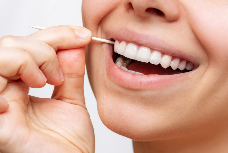 Close up of woman's smile with toothpick at corner of mouth